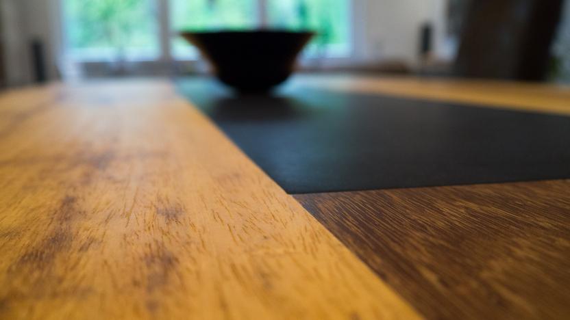 Makroaufnahme der Holzoberfläche eines Tisches. Detailansicht der Holztextur eines Tisches mit einem dunklen Mittelstreifen und unscharfer Schale.