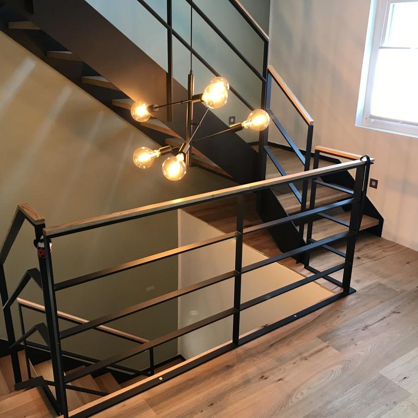 Treppenhaus mit dunklem Geländer und Holzfußboden