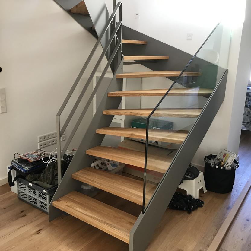 Offene Treppe im Raum mit grauem Geländer und Holzstufen