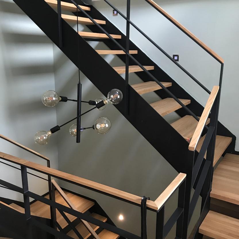 Modernes Treppenhaus mit Holzstufen und schwarzem Geländer