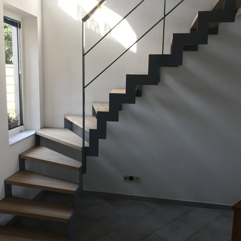 Treppe mit grauen Stufen und dunklem Geländer