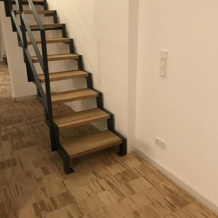 Holzstufen einer Treppe mit dunklem Geländer