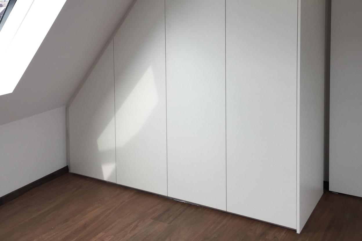 Weißer Dachschrägenschrank Weißer Dachschrägenschrank neben Fenster