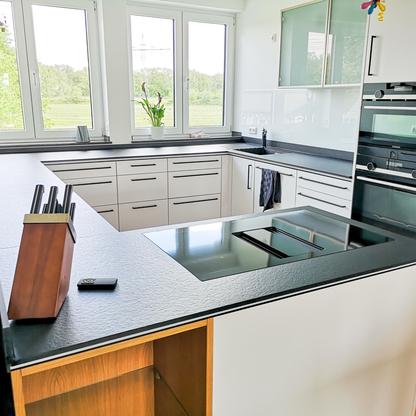 Eck-Küchenzeile mit dunkler Arbeitsplatte und weißen Schränken