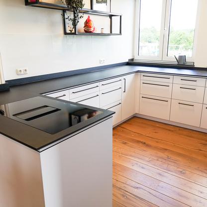 Küchenzeile mit weißen Fronten und dunkler Arbeitsplatte