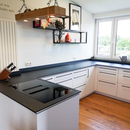 Küchenzeile mit weißen Fronten und dunkler Arbeitsplatte über Eck