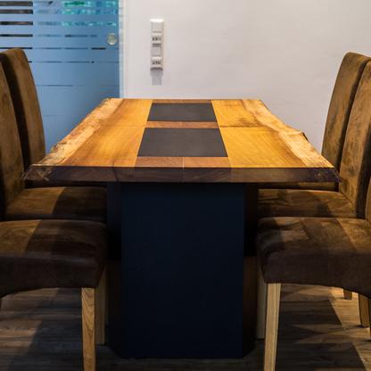 Ein Holztisch mit schwarzem Designelement, umgeben von braunen Samtstühlen.