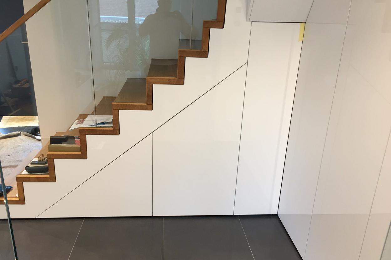 Moderne Treppenstufen aus Holz neben einer glatten weißen Schrankwand.
