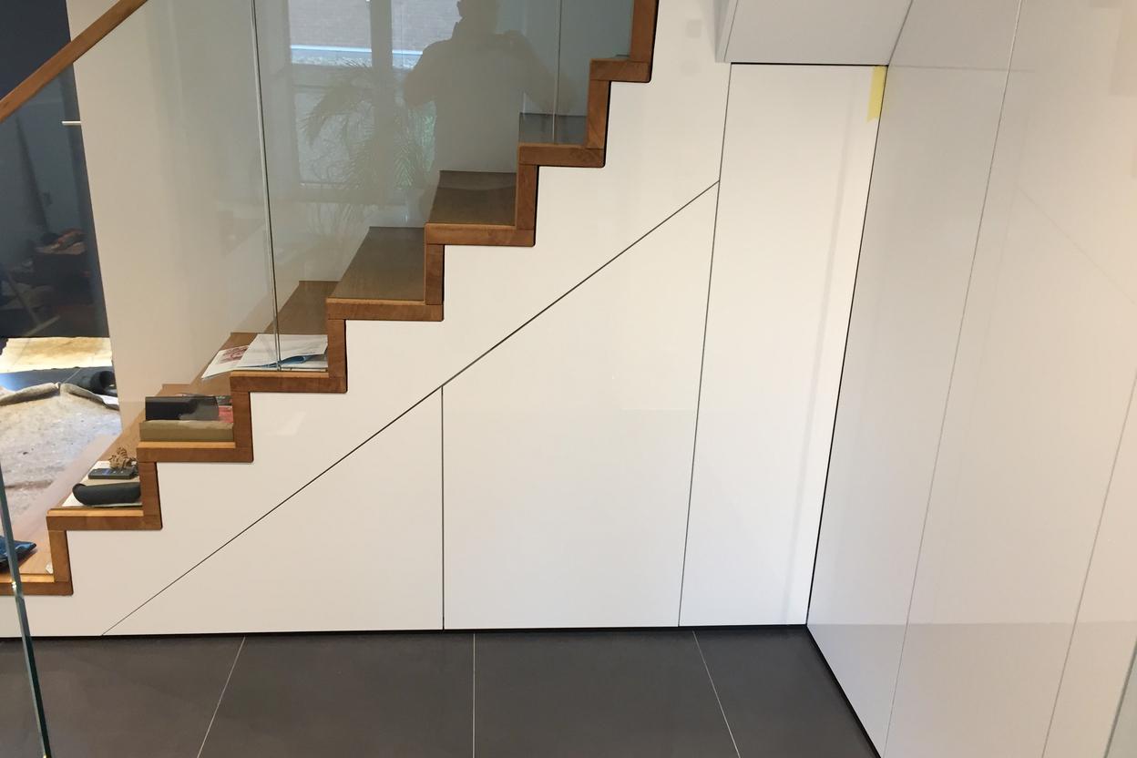 Moderne Treppenstufen aus Holz neben einer glatten weißen Schrankwand.