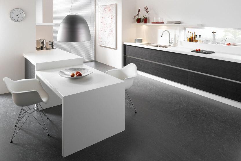 Impression einer einzeiligen Küchengestaltung in schwarz-weiß mit Esstisch für Zwei