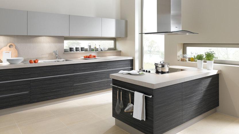 Impression einer Küchengestaltung mit Kochinsel mit Edelstahlabzug und dunklen Fronten