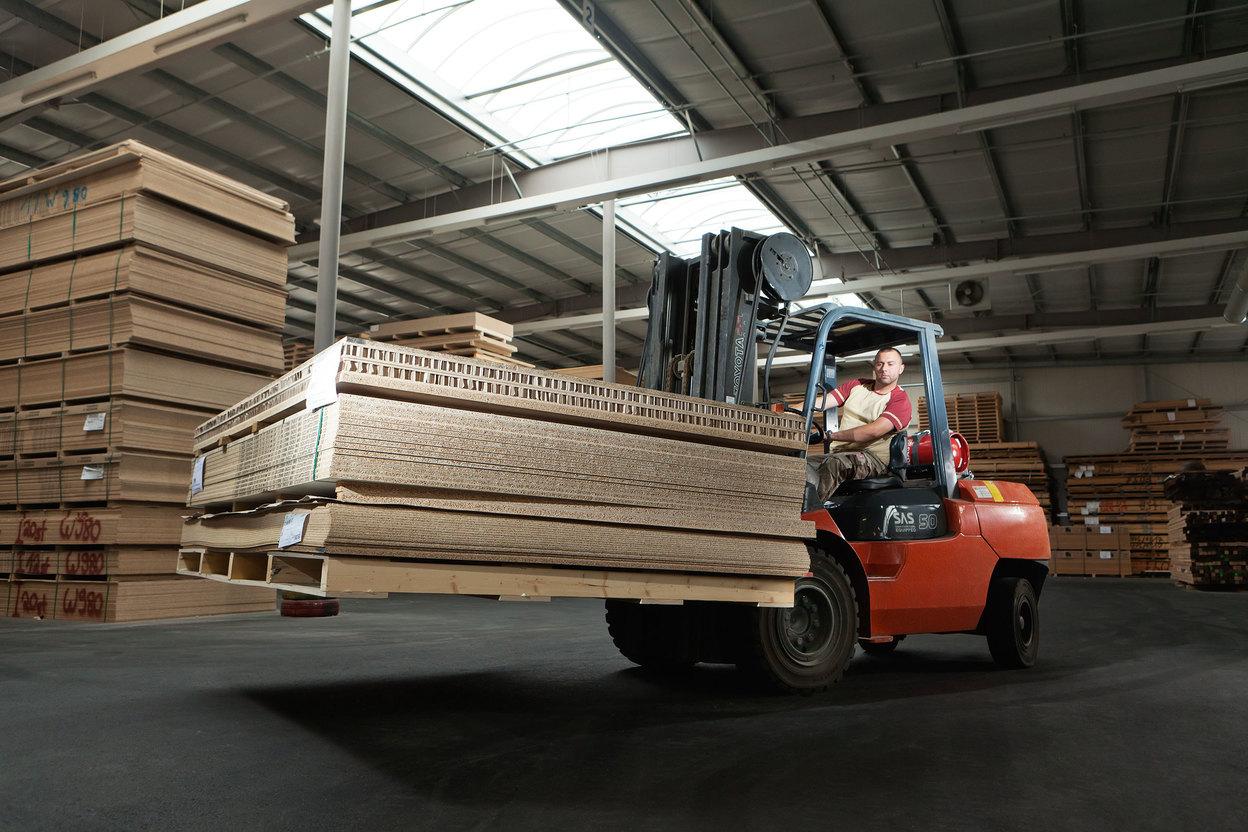 Gabelstapler transportiert Holz und Holzpaletten in Lager